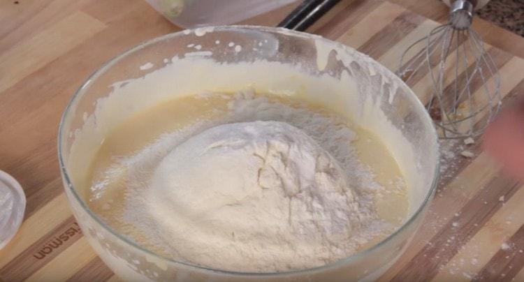 Add sour cream to the egg mass, as well as flour and baking powder.