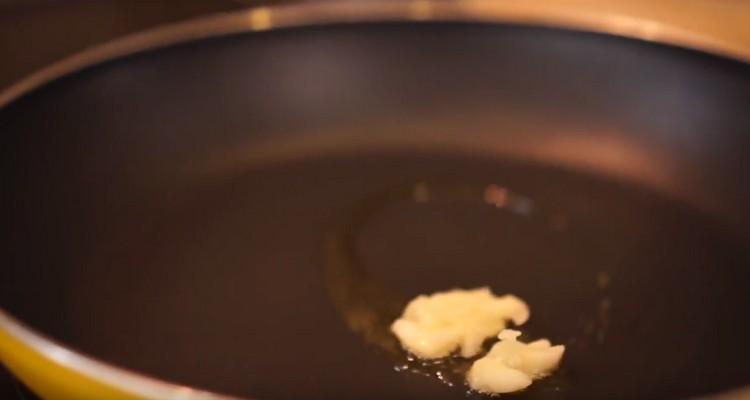 Put the crushed clove of garlic in the pan.