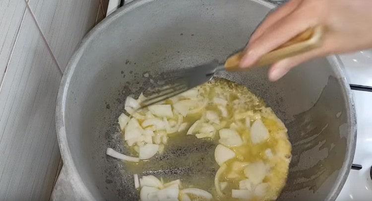 In oil, fry the onion sliced in half rings.