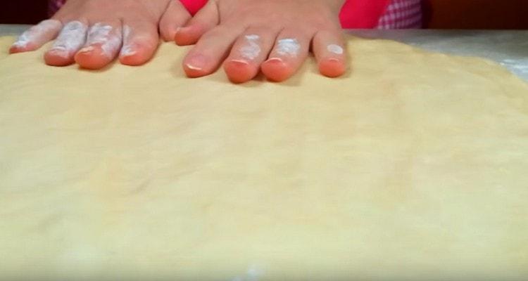 We put the dough on the table and stretch it into a rectangle.