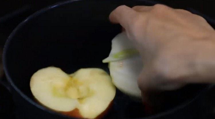 In a stewpan spread half a apple and half an onion.