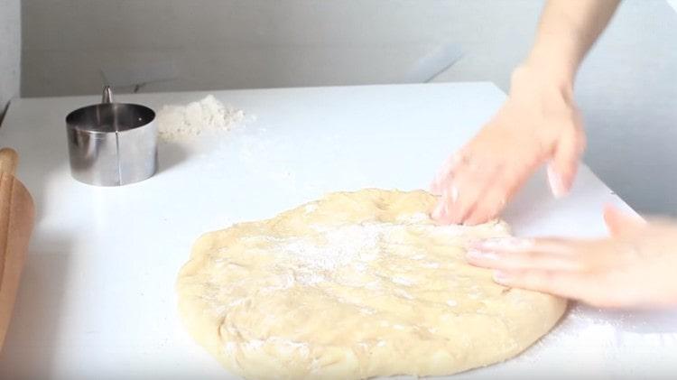 We spread the dough on the work surface, distribute it by hand.