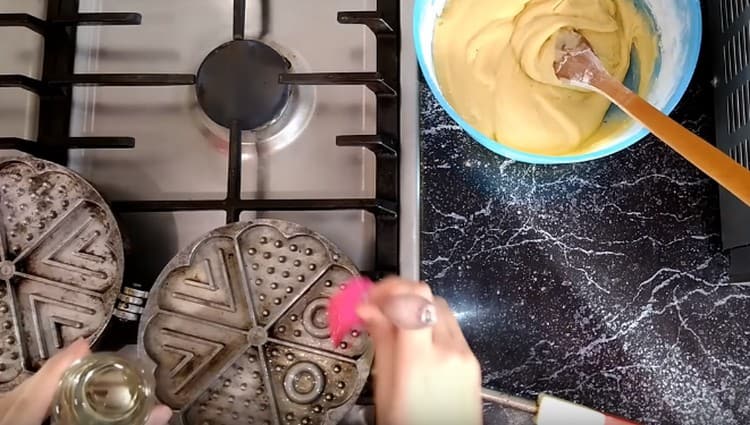 We heat the waffle iron and grease it with vegetable oil.