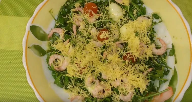 Ready salad with arugula, shrimp and cherry tomatoes sprinkle with grated cheese.