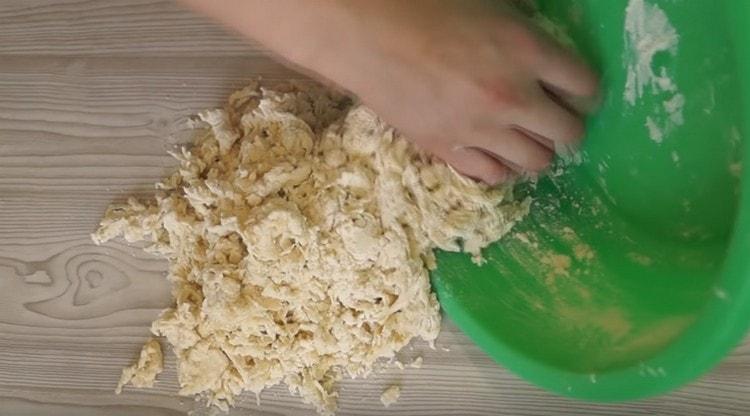 We shift the thickened dough onto the table and continue to knead with our hands.