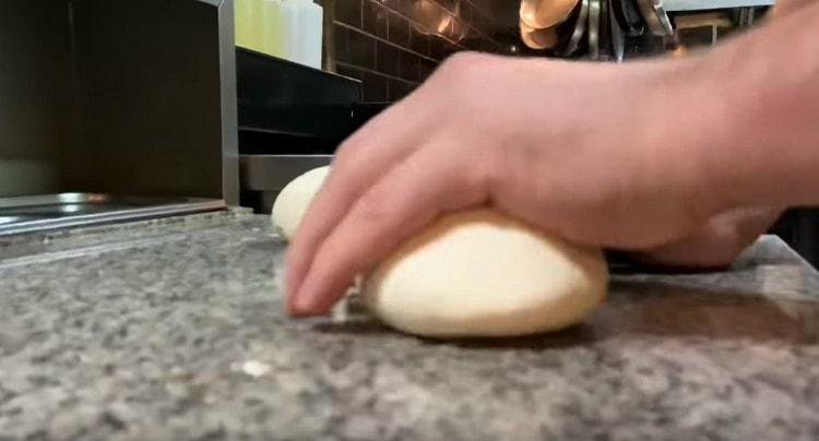 We roll pieces of dough on the table.