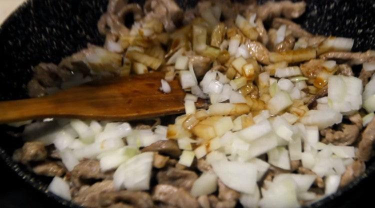 Add onion and soy sauce to the meat in the pan.