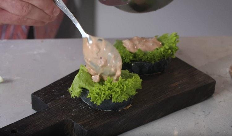 On a bun, put a spoonful of sauce, a sheet of salad, and then again a spoonful of sauce.