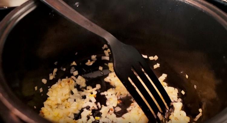 Fry chopped onions in a multicooker bowl.