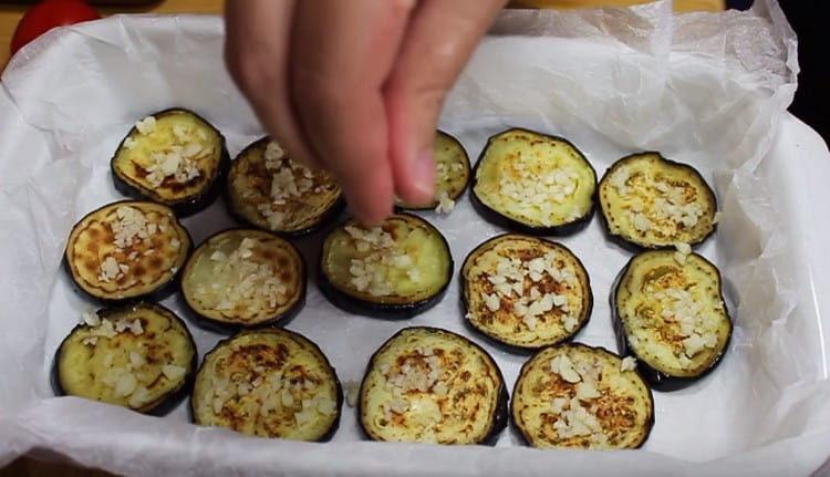 Salt the eggplant slices, put the garlic on them.