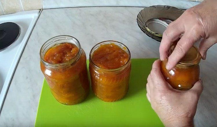 We lay pumpkin jam with dried apricots in sterilized jars and twist the lids.