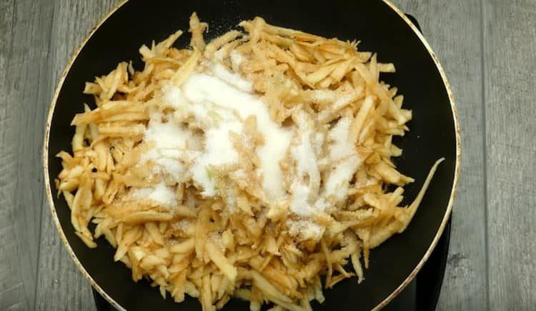 Stew apples in a pan, adding sugar to them.