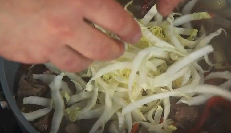 Add cabbage to meat with vegetables.