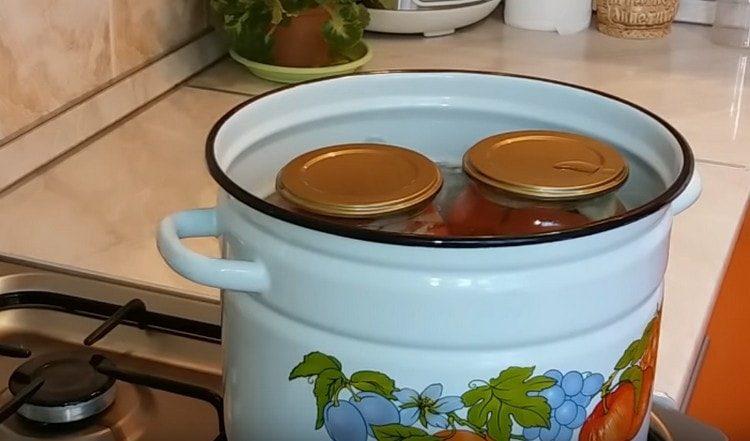 We sterilize jars with tomatoes.