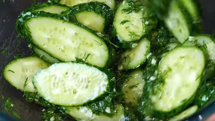 We spread the cucumbers in the marinade and mix.