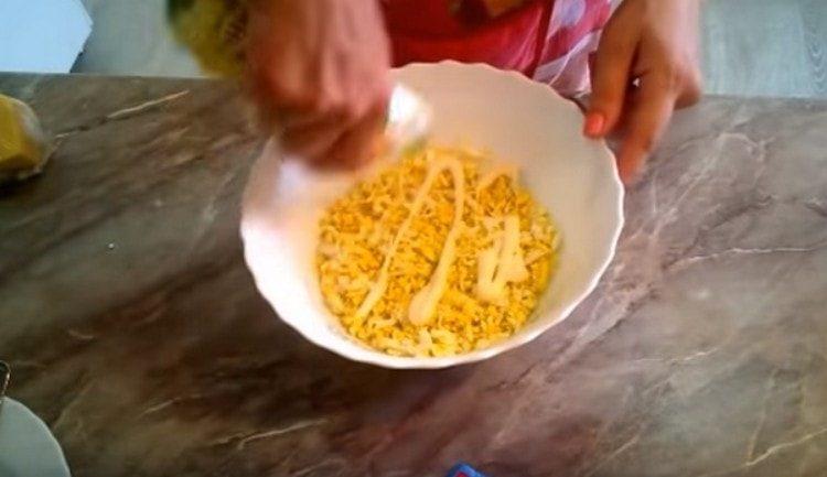 We form the first layer of salad from the eggs and grease it with mayonnaise.