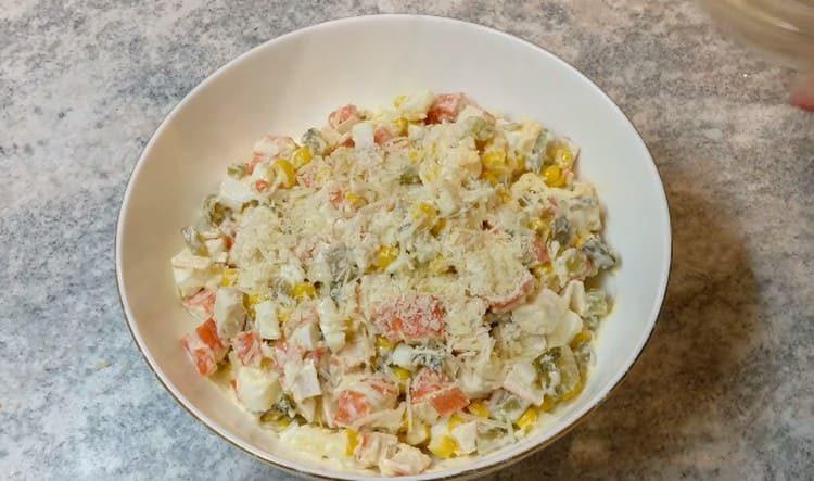 Sprinkle the finished salad with crab sticks and cucumbers with grated cheese.