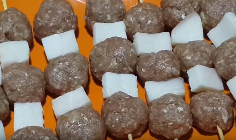 On wooden skewers we string in turn meat balls and pieces of fat tail.