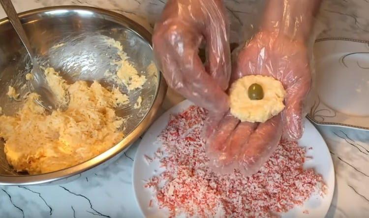 From the cheese and egg mass, we form a cake and put the olive in the center.