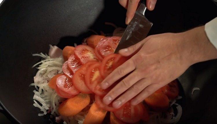 On top of the carrots, spread the sliced tomato.