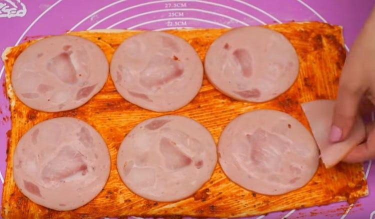 On the dough, lay out the sliced ​​boiled sausage.