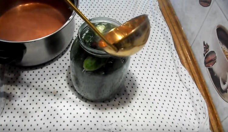 Boiled marinade pour jars of cucumbers, adding vinegar to it.