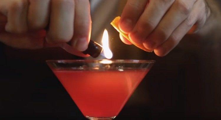directly over the glass, lightly burn the orange zest.