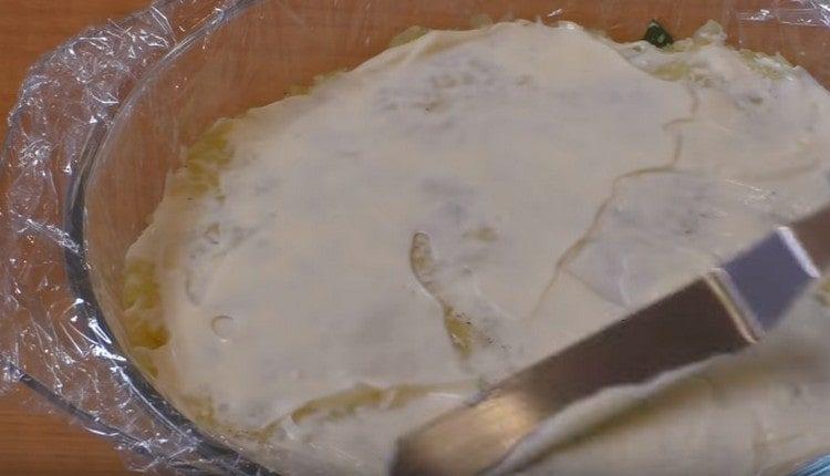 Spread a layer of grated potatoes, coat with mayonnaise