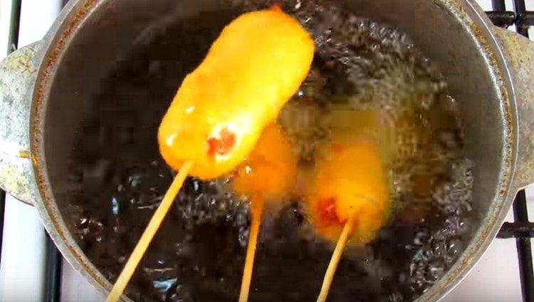 Dip sausages in batter and fry in vegetable oil.