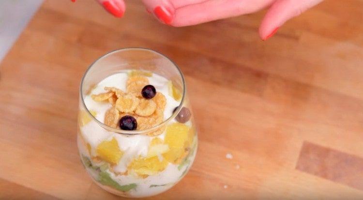 We decorate a fruit salad with cereals and blueberries.