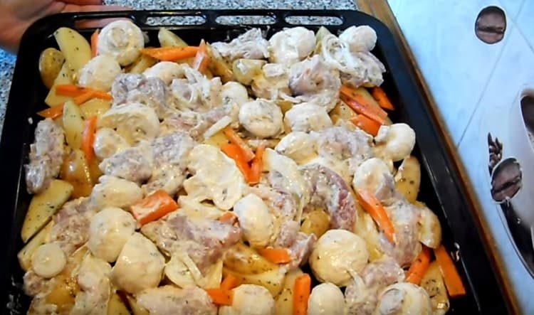 On top of the potatoes we distribute meat with onions, mushrooms.
