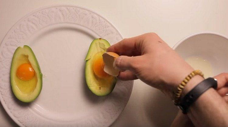 In each half of the fruit, beat the egg.