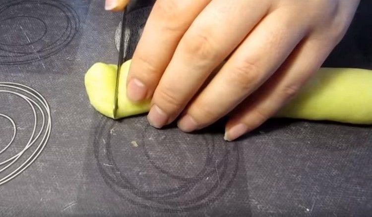 We divide the dough into portions, roll sausages out of them and cut into small pieces.