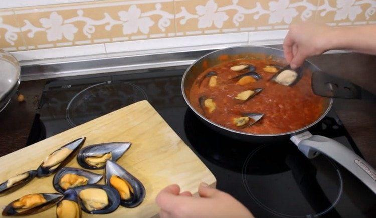 We spread the mussels in tomato sauce and simmer for a few more minutes under the lid.