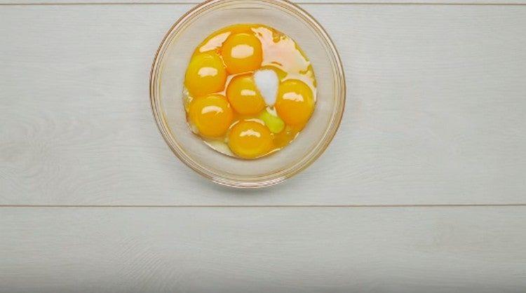 In a bowl, lay one egg and egg yolks, as well as salt.