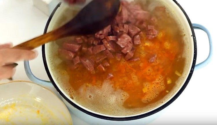 We spread sausage in a saucepan with soup.